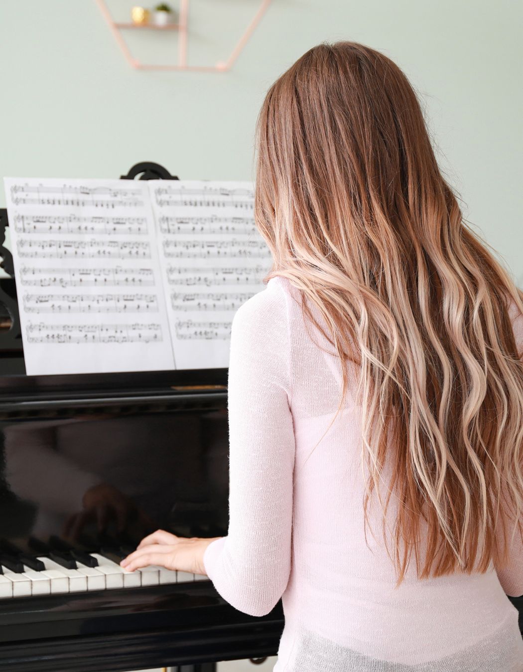 A woman plays a large, dark wood piano, with her back to the camera. For Blog: The future of the financial planning profession